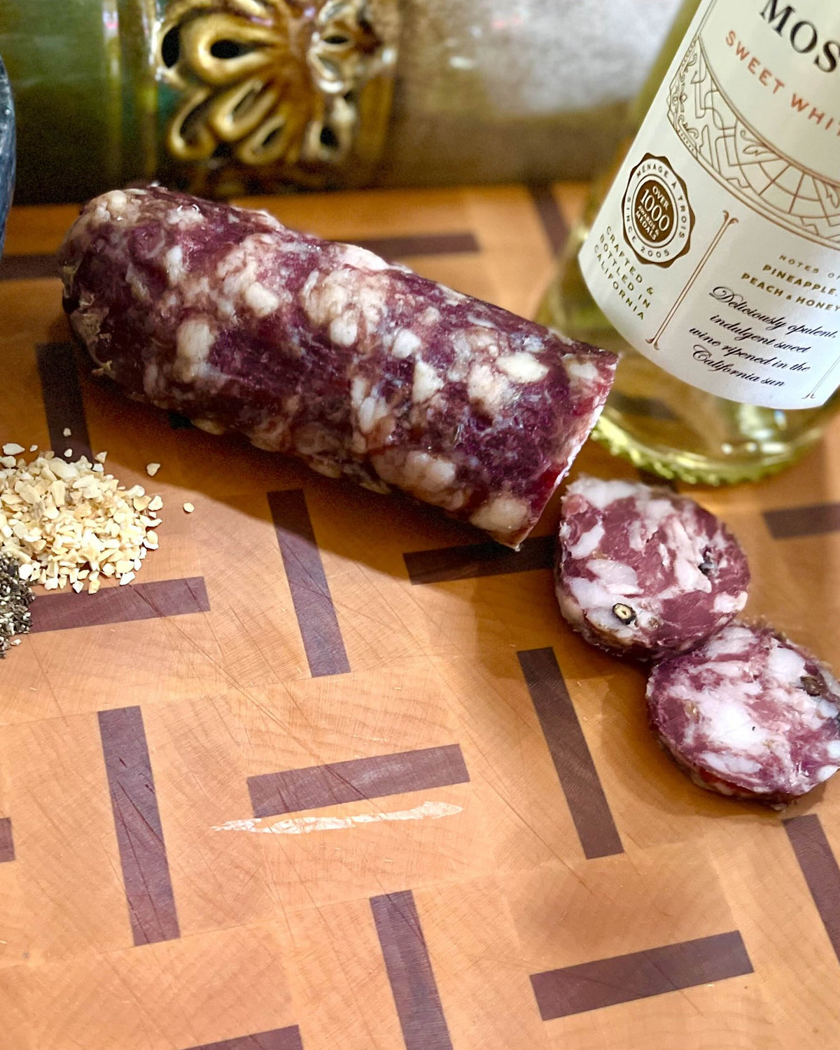 A Dolce chub cut open on a butcher block, with garlic and cracked pepper, and a bottle of moscato behind