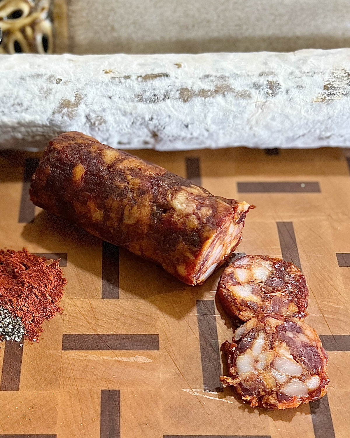 A Fustos chub cut open on a butcher block, with paprika, oregano and garlic beside it