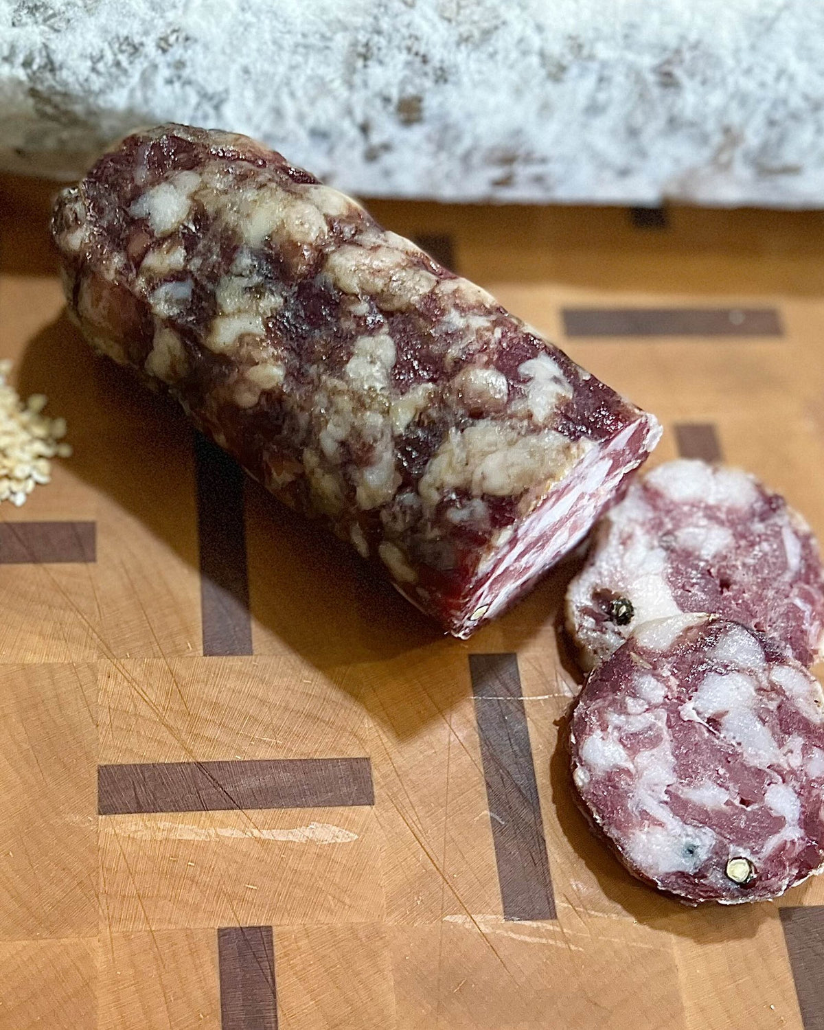 A Marathos chub cut open on a butcher block, with fennel seed, peppercorn and garlic beside it