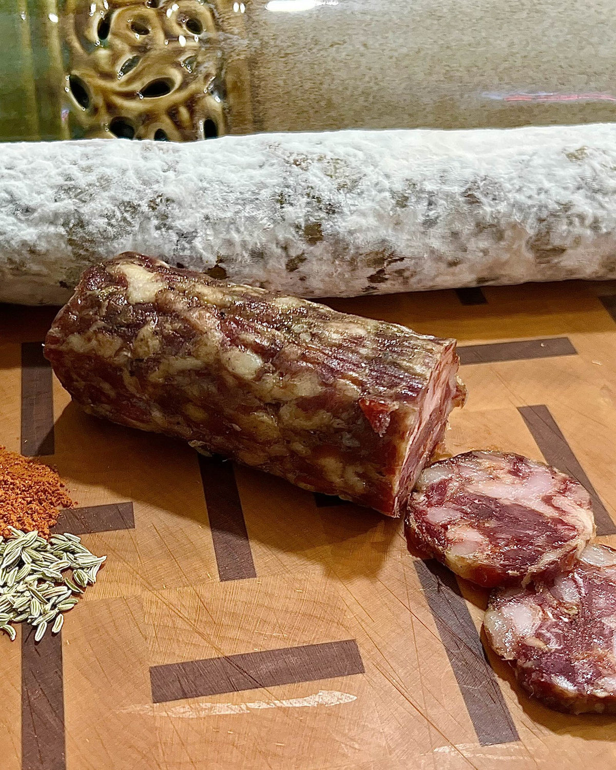 A Tata chub cut open on a butcher block, with cayenne, Calabrian chili and fennel seed beside it