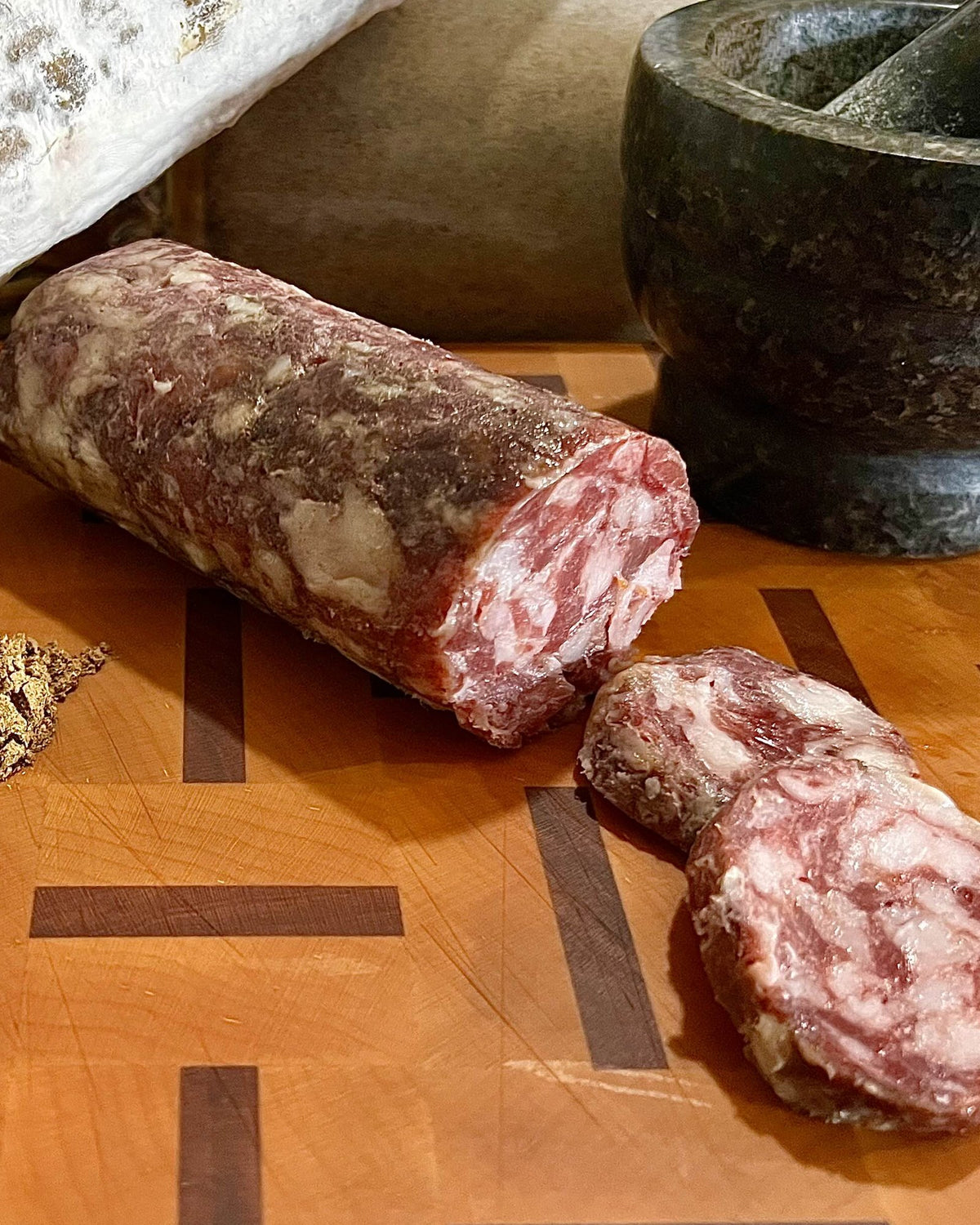 A Toprak chub cut open on a butcher block, with cumin, mace, garlic and juniper berries beside it